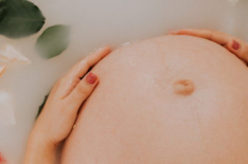 Buik van een zwangere vrouw in een melk bad