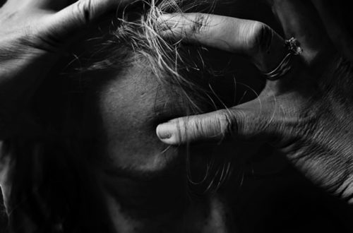 Zwart wit foto van man met de handen op zijn hoofd door te veel stress