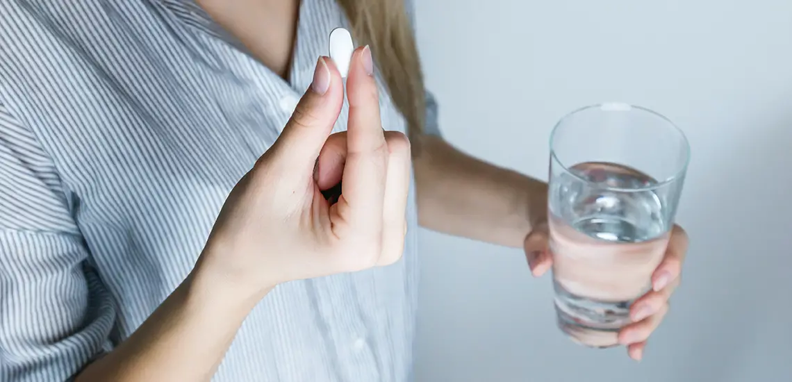 Vrouw met pil en glas water